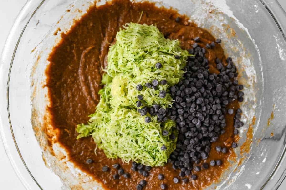 zucchini and chocolate chips being folded into batter.