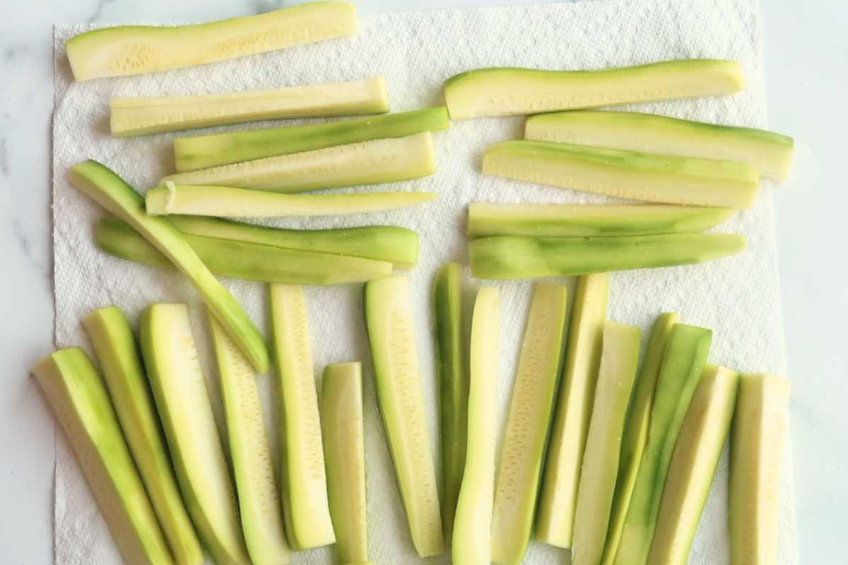 raw zucchini fries on a paper towel.