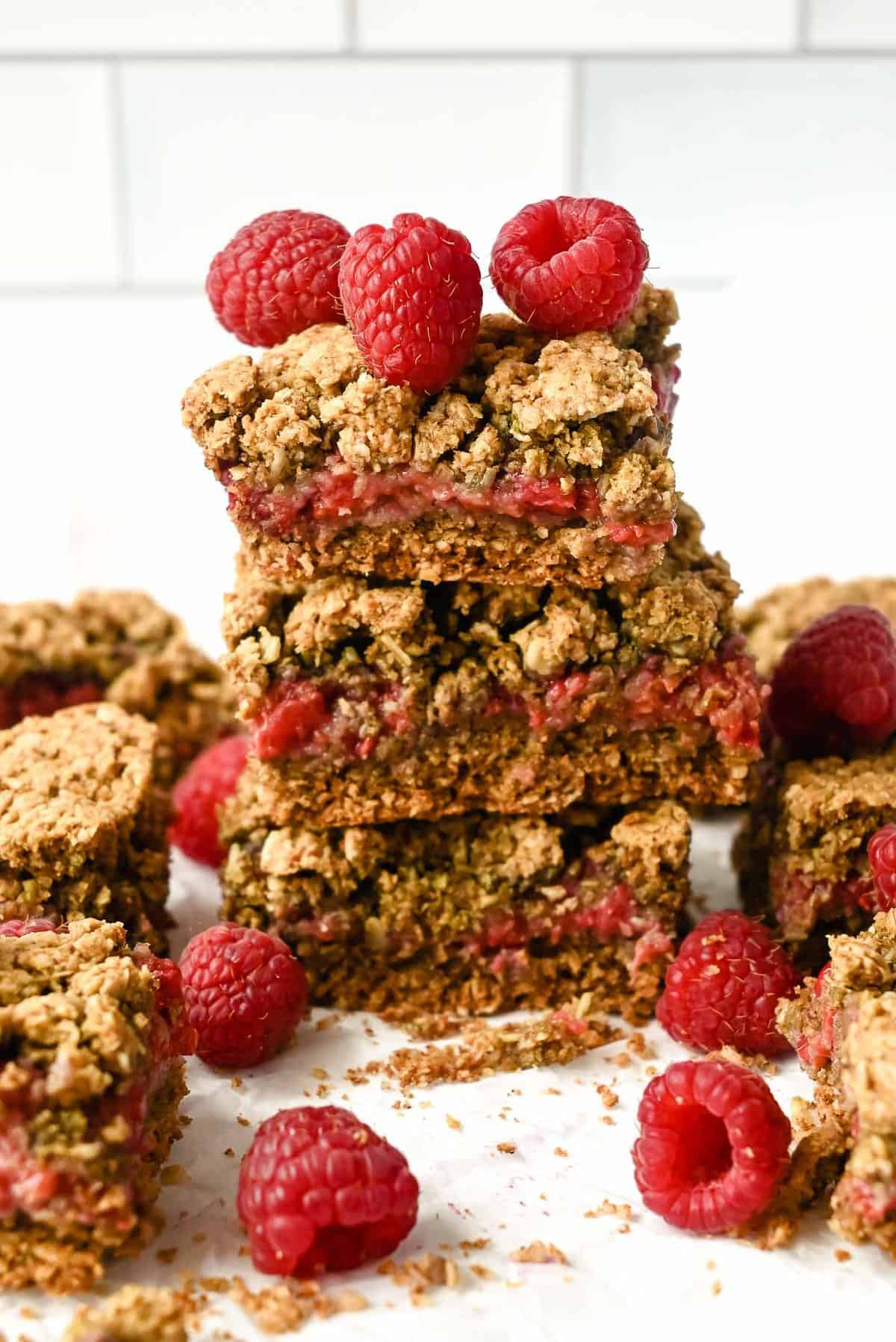 stack of raspberry oat bars with fresh raspberries on top.