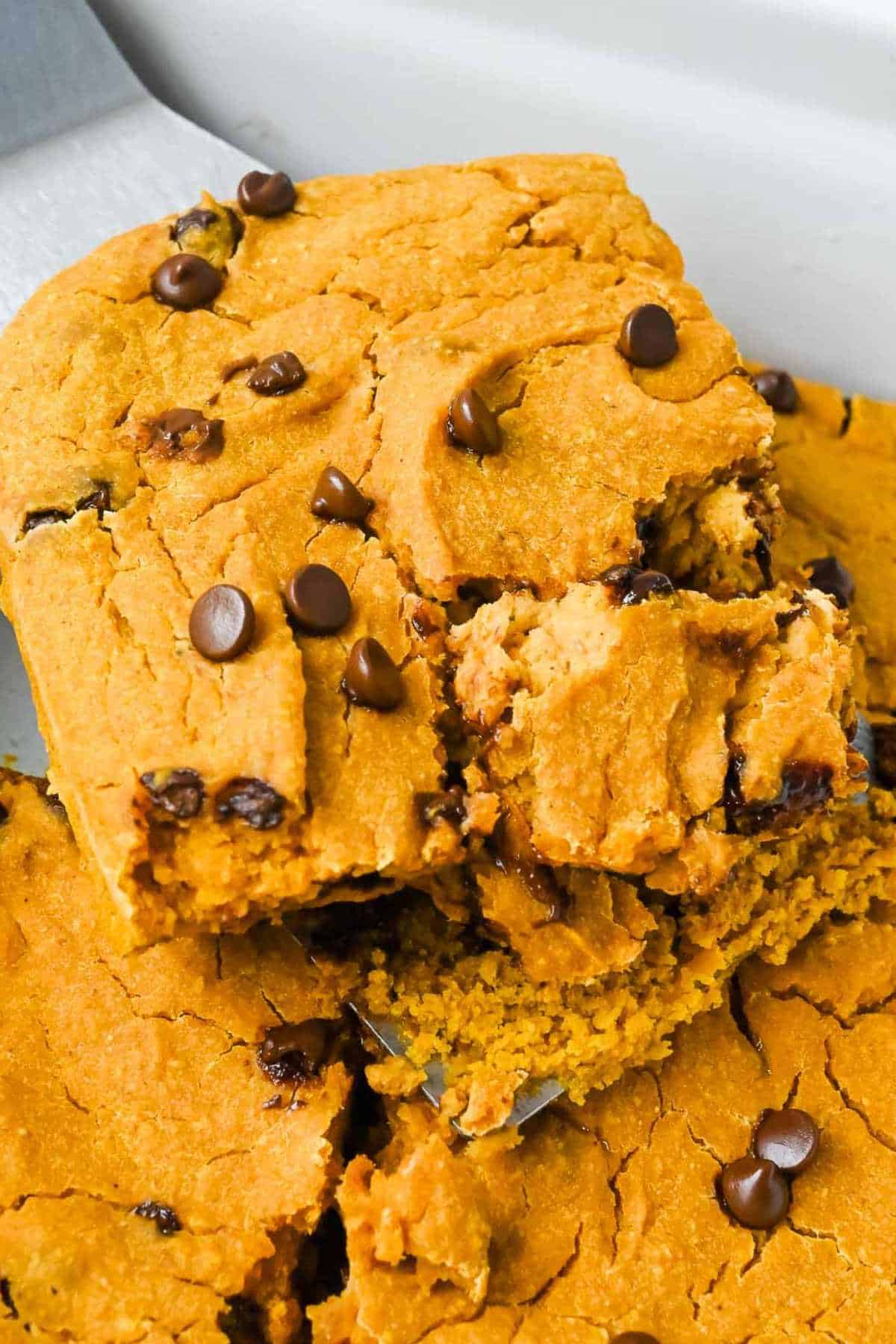slice of pumpkin baked oatmeal on a spatula in a white baking dish.