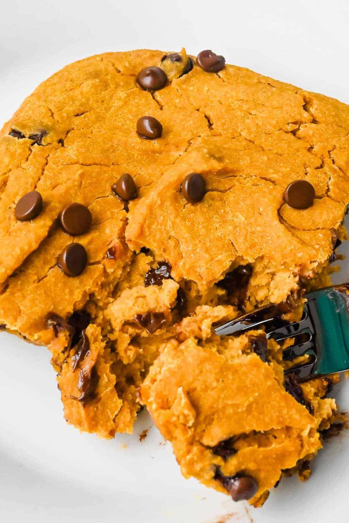 slice of pumpkin baked oatmeal with chocolate chips on a white plate with a fork holding a piece.