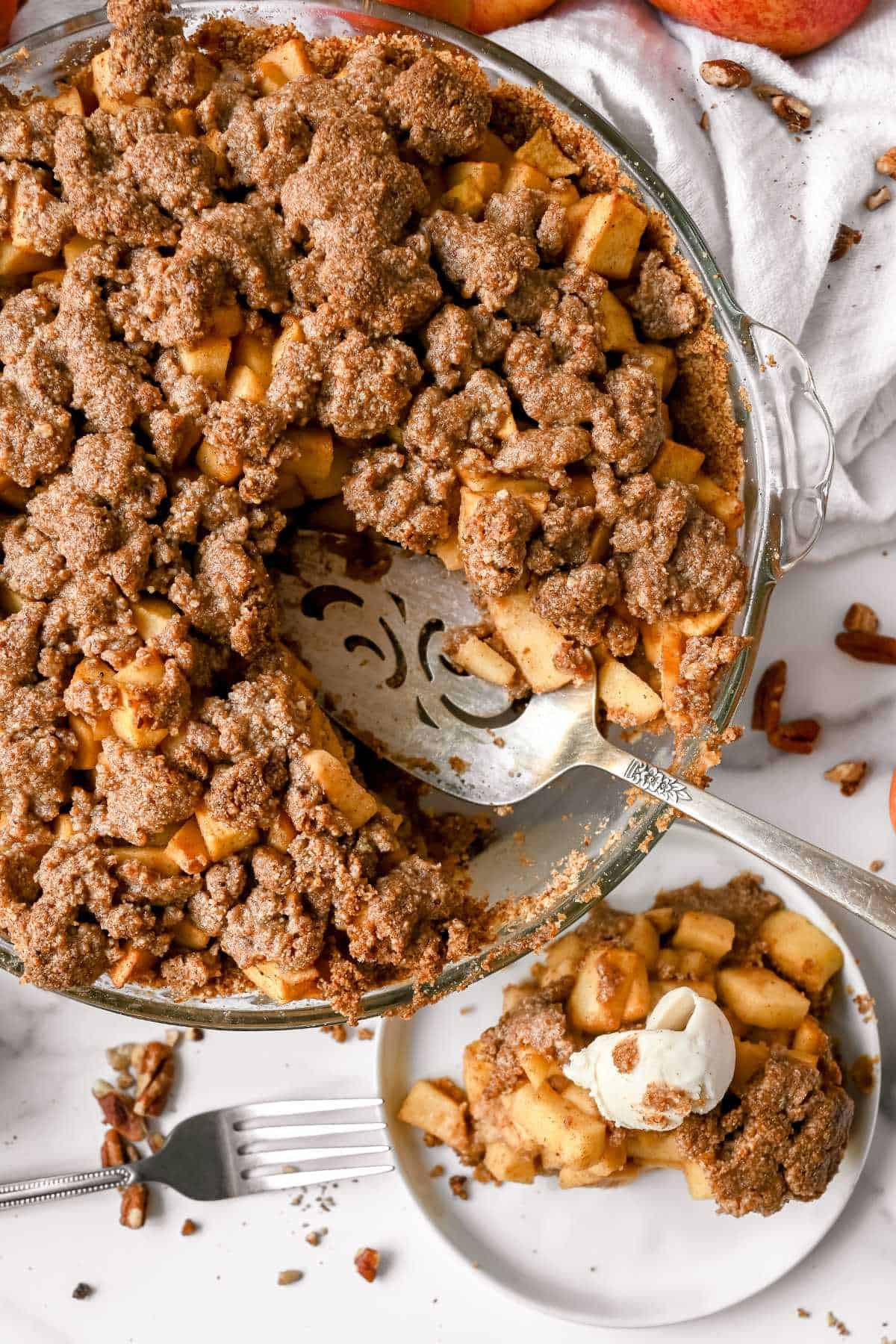 top view of healthy apple pie with a slice on a white plate.