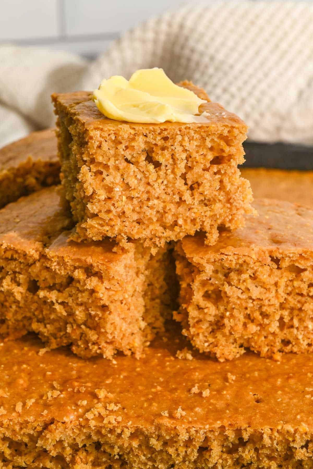 three slices of cornbread in a stack with butter on the top.