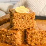 close up of three slices of cornbread in a stack with butter on the top.