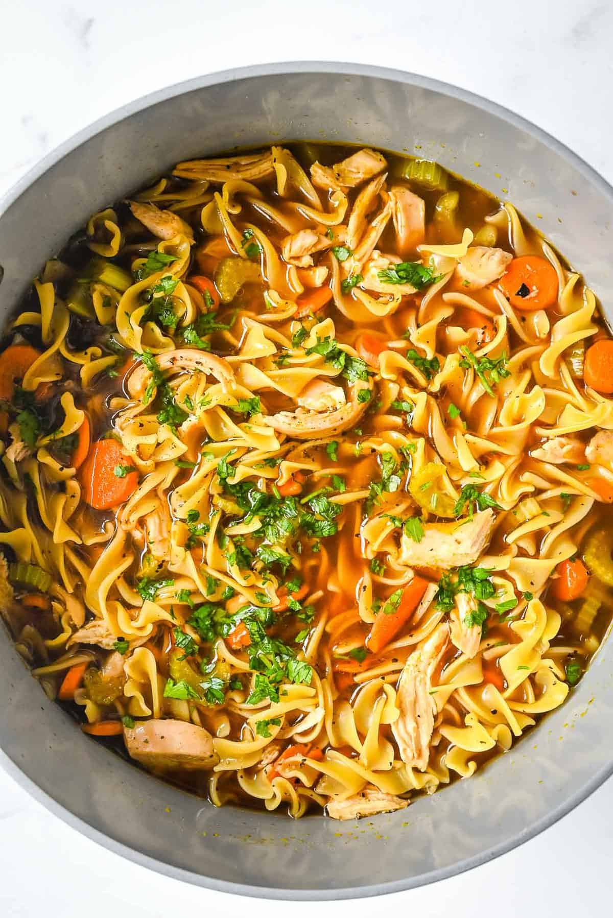 pot of bone broth chicken soup topped with parsley.