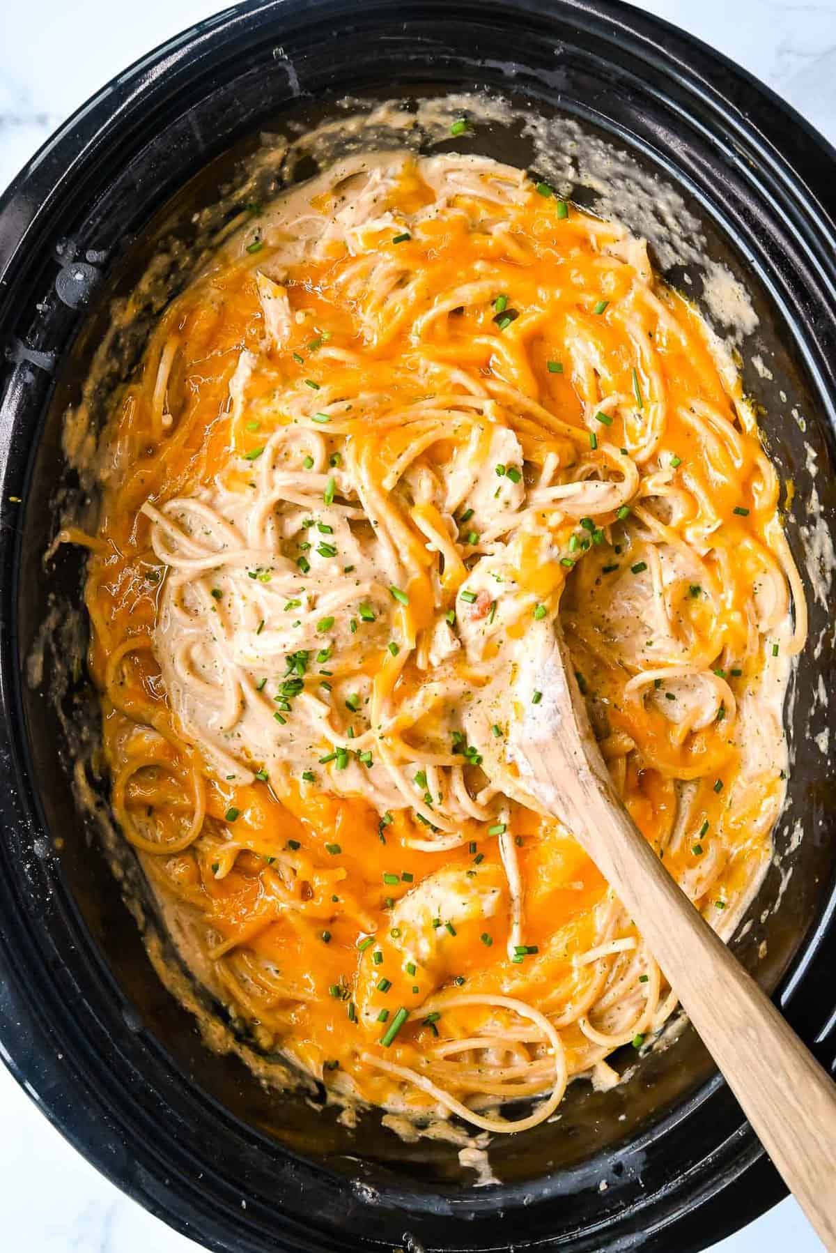 crock pot chicken spaghetti topped with parsley in a slow cooker.
