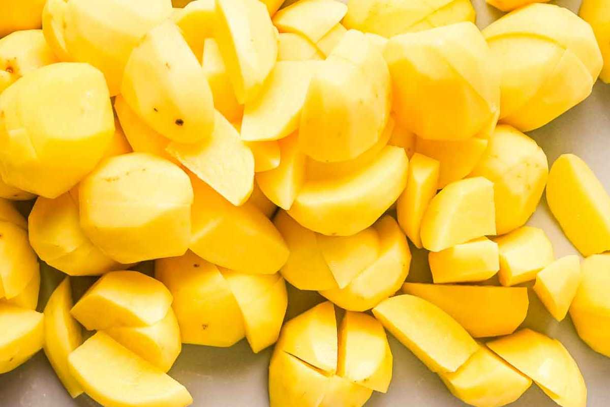 quartered yellow potatoes on a gray cutting board.