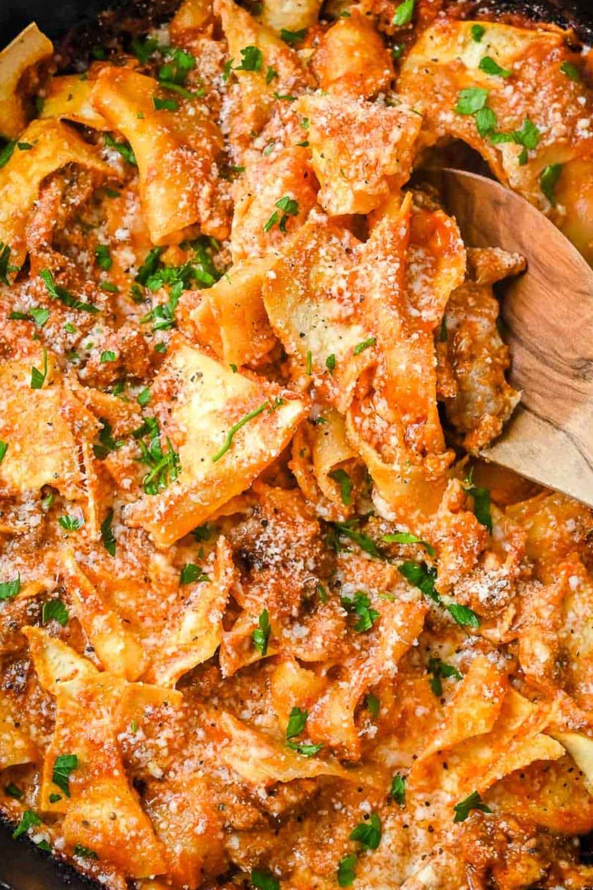 close up shot of lazy lasagna in a skillet with a wooden spoon.