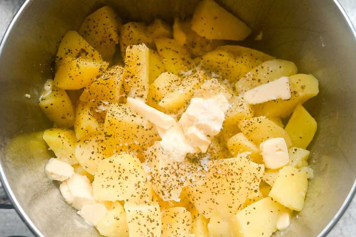 cooked potatoes with butter and seasoning in a pot.