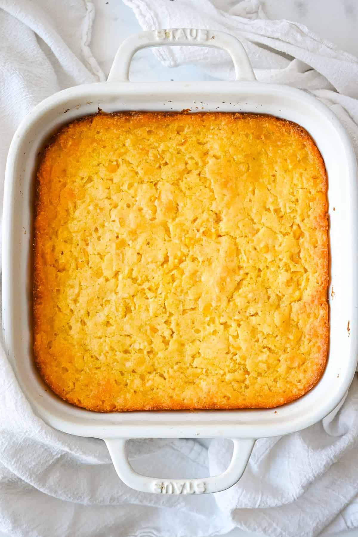 up down shot of healthy corn casserole in a white pan on a white background.
