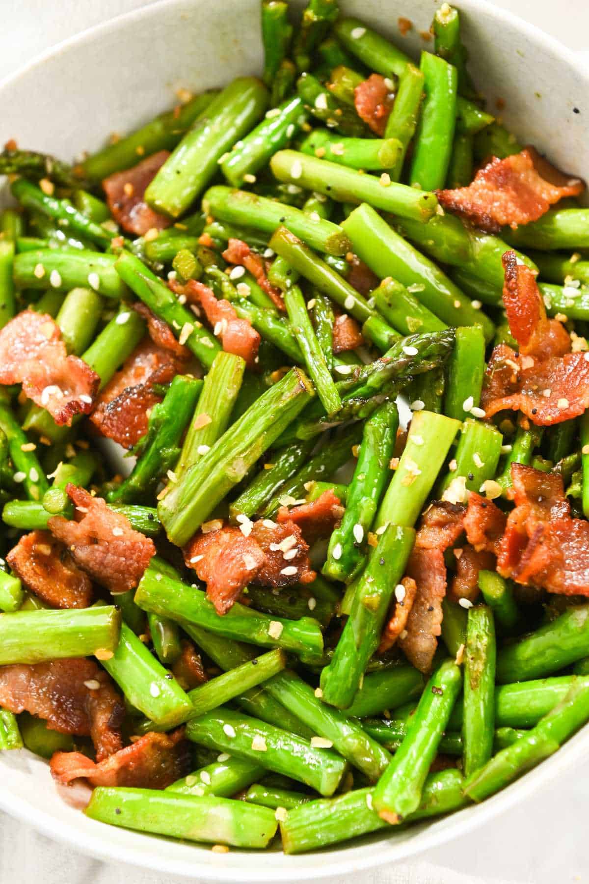 bacon and asparagus topped with sesame seeds in a white bowl