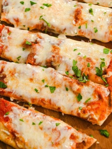 close up of air fryer naan pizza on a wood cutting board.