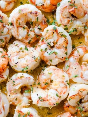 close up shot of pan seared shrimp topped with parsley.