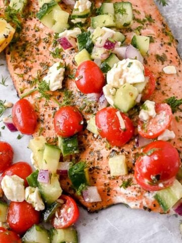 close up shot of greek salmon with cucumber tomato salad topping.