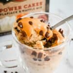 close up shot of pancake in a glass mug with spoon and box in the background.