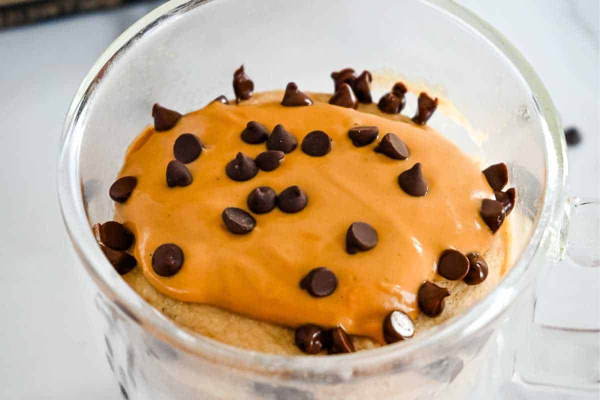 pancake in a mug topped with peanut butter and chocolate chips.