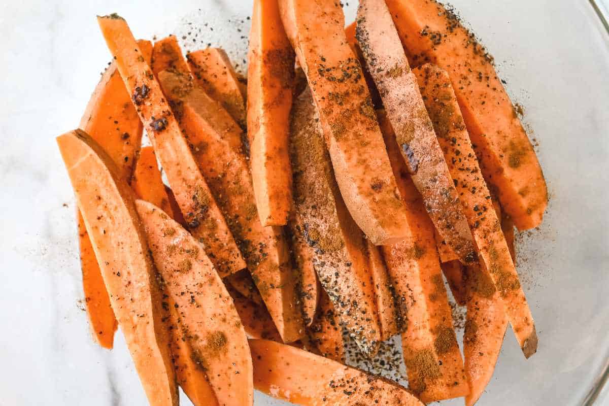 close up of seasoned sweet potatoes in a bowl.