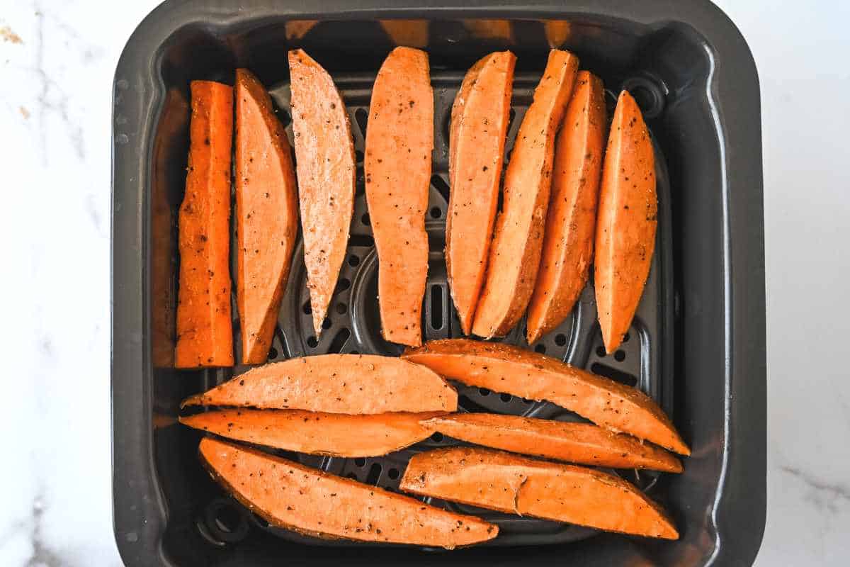 rows of air fryer sweet potato wedges in a black basket.