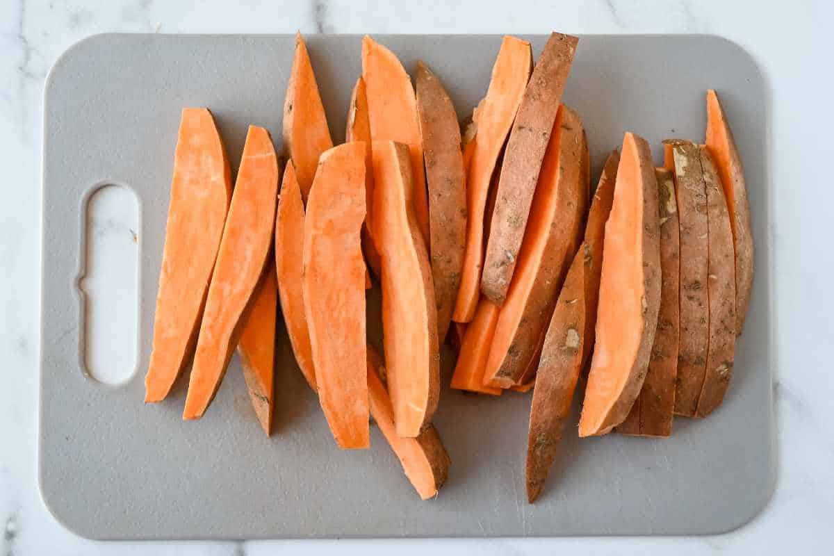 sweet potato wedges on a gray cutting board.