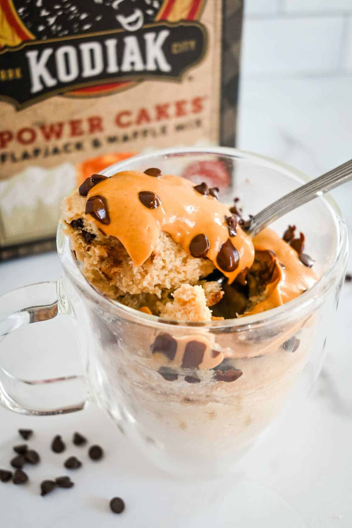 full shot of pancake in a glass mug with spoon and box in the background.