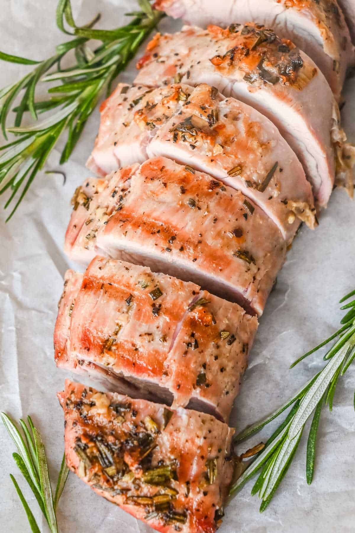 grilled pork medallions with rosemary on parchment paper.