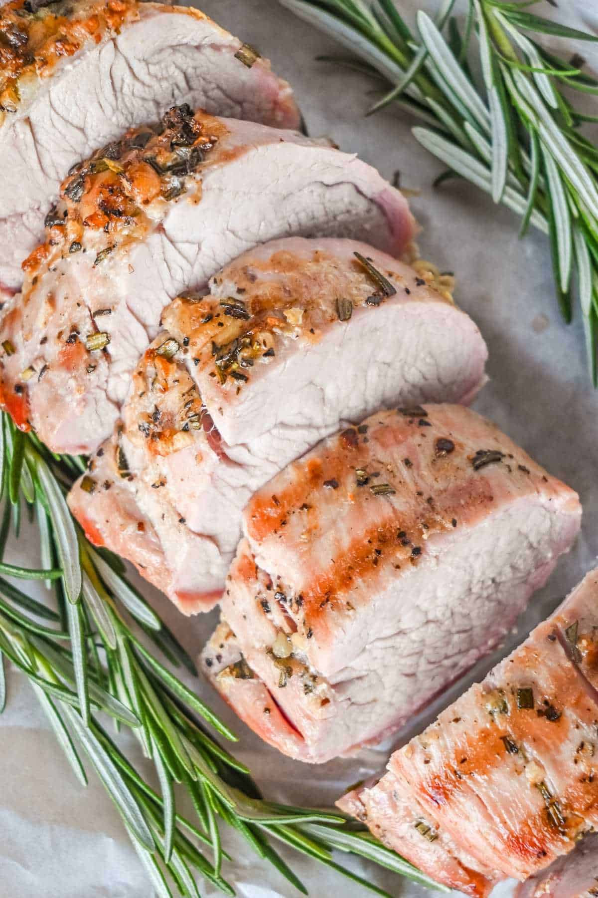 grilled pork medallions with rosemary on parchment paper.