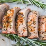 close up shot of pellet grill pork tenderloin medallions with rosemary on parchment.