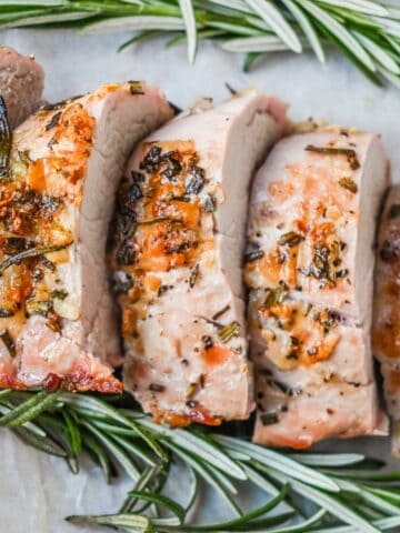 close up shot of pellet grill pork tenderloin medallions with rosemary on parchment.