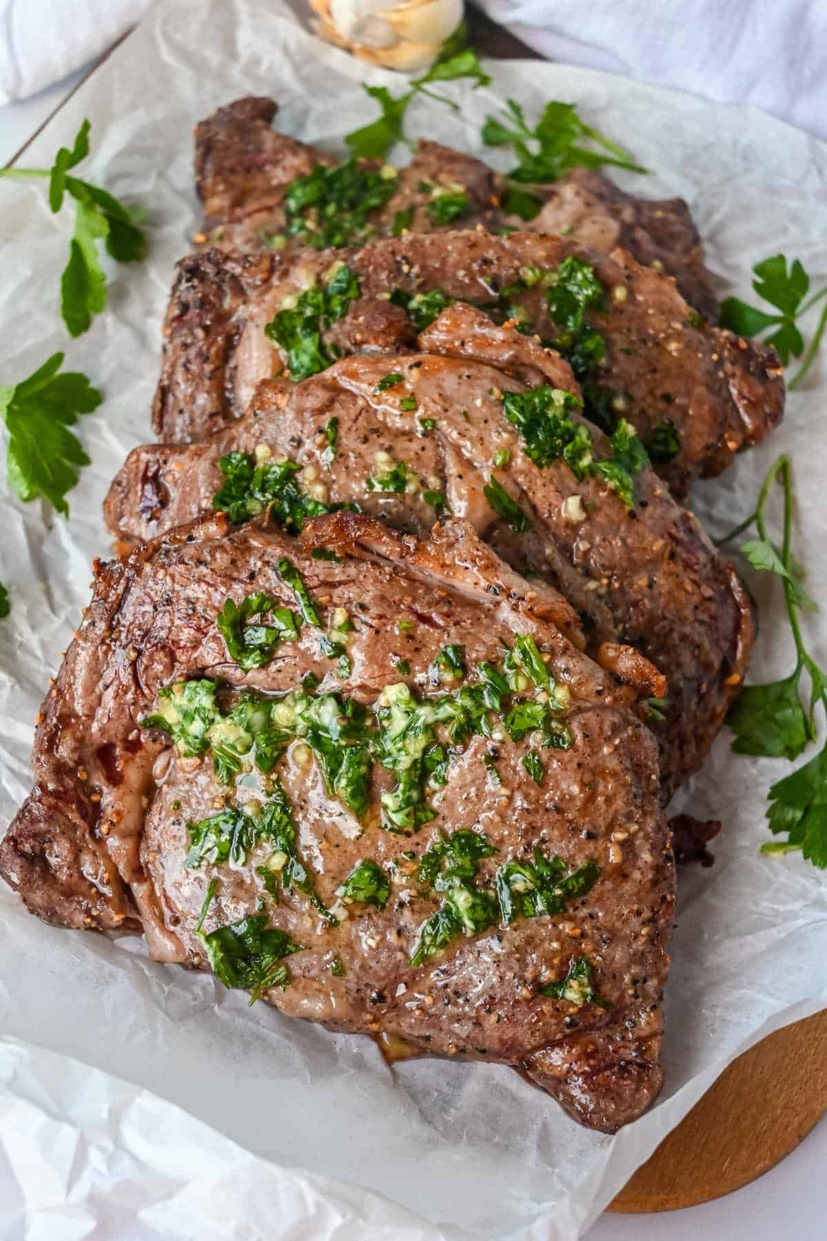full ribeye steak topped with her butter on parchment paper.