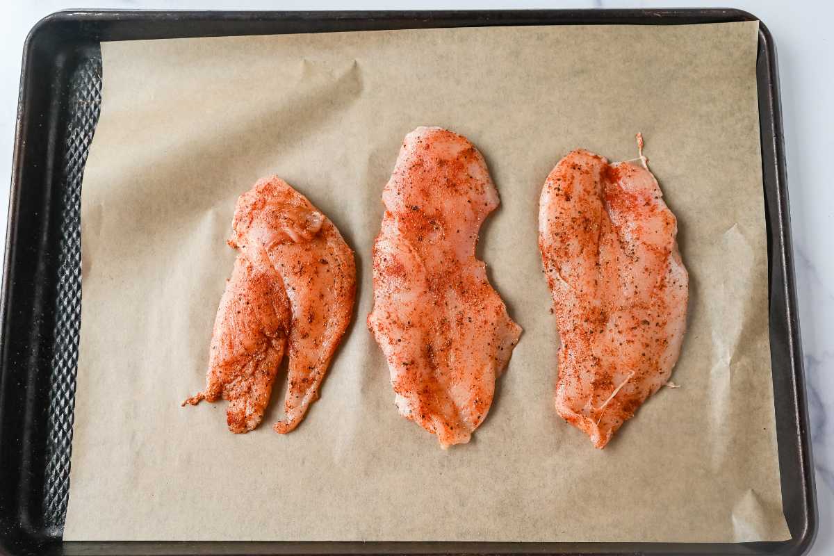 thin chicken breast on a baking sheet with parchment paper.
