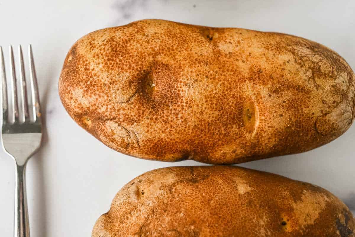 raw russet potatoes next to a fork.