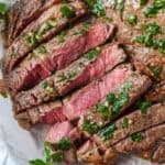 close up of sliced air fryer ribeye topped with butter and fresh herbs.
