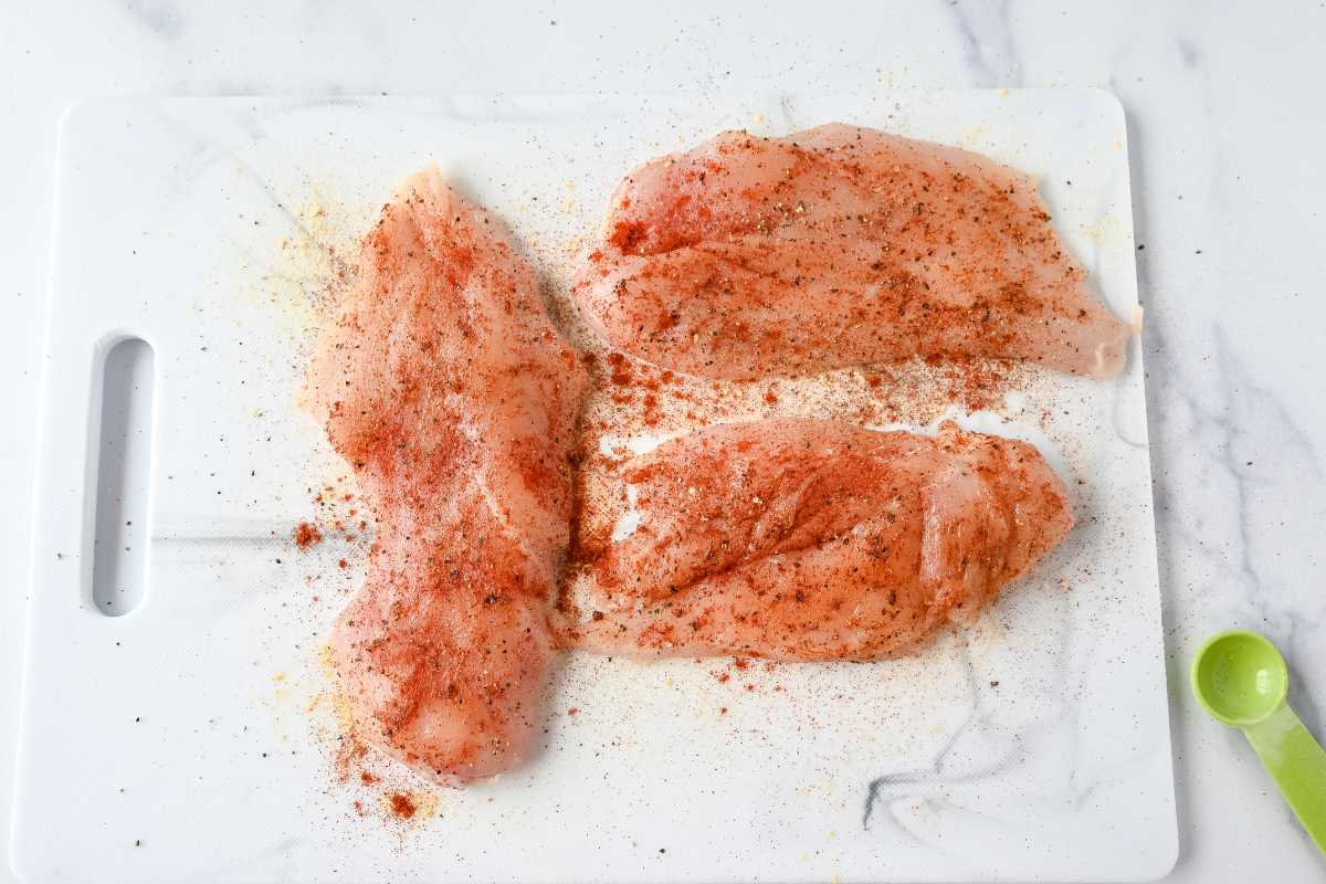 seasoned raw chicken on a cutting board.