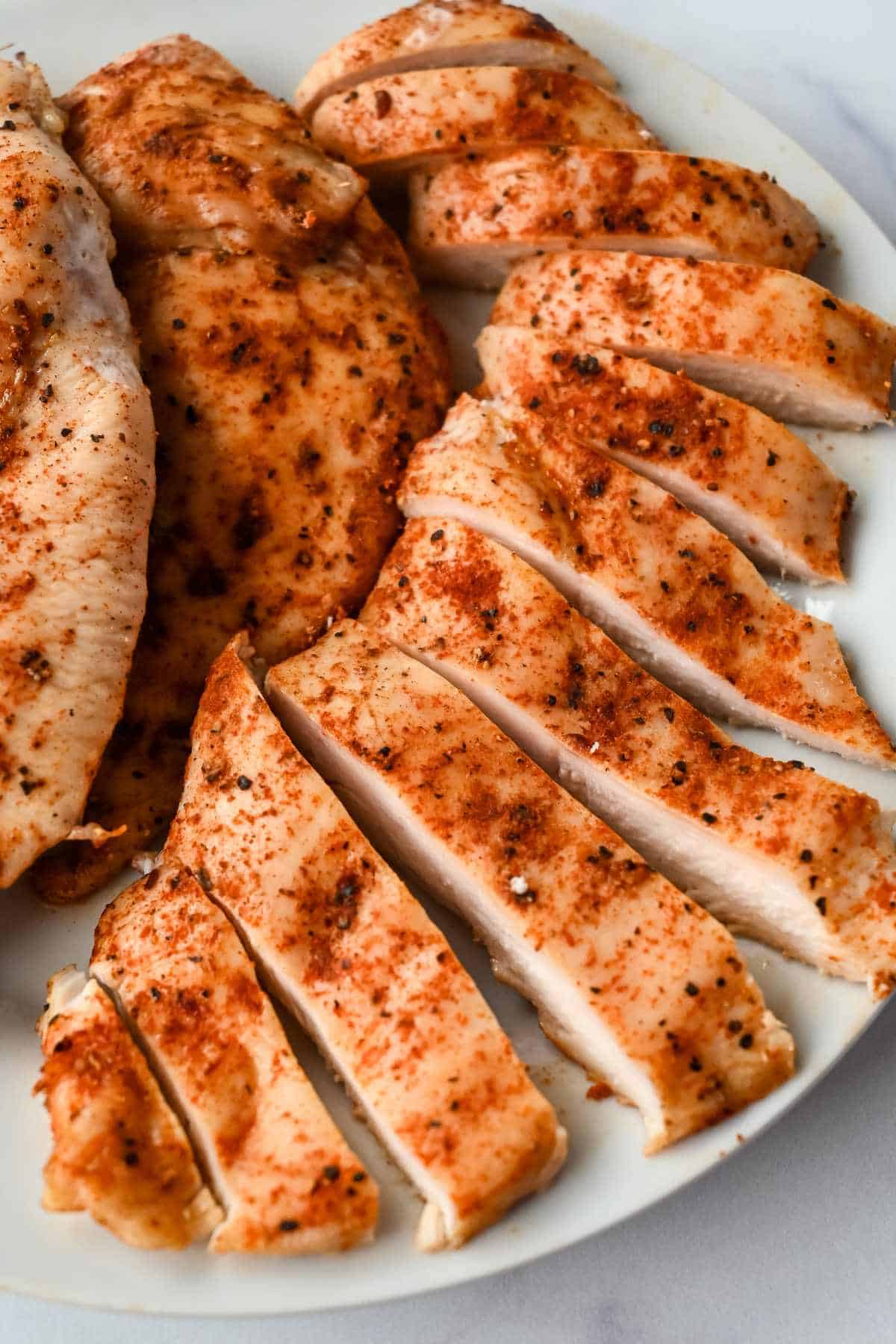 pieces of baked thin sliced chicken breast on a white plate.