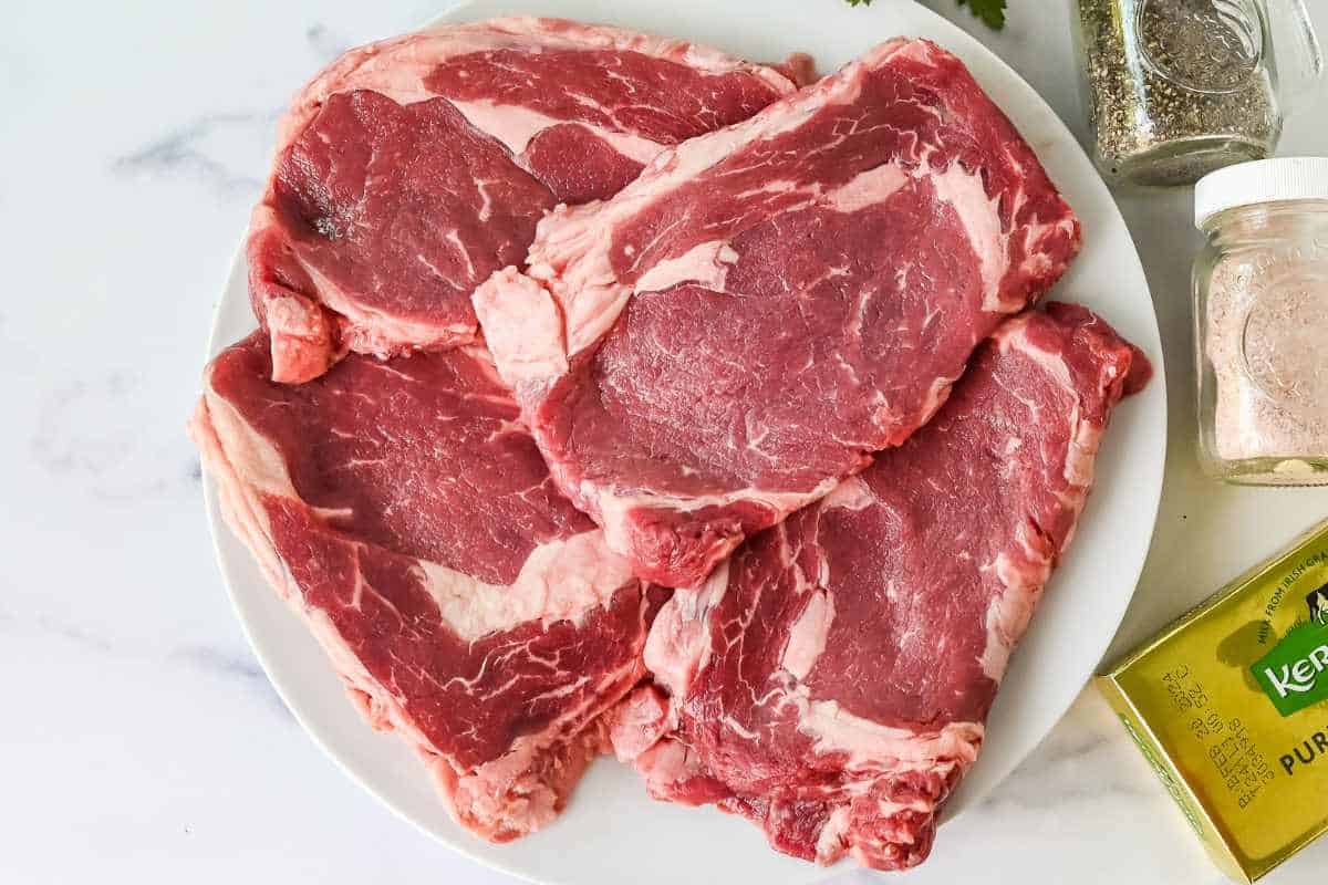 raw ribeye steak on a white plate.