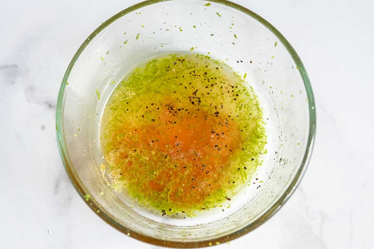 red cabbage slaw dressing in a glass bowl on a white background.