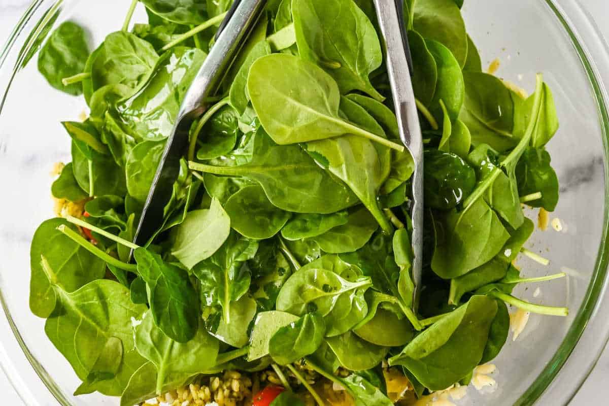 spinach and tongs in a glass bowl.