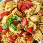 featured image close-up of tortellini pesto salad with tomatoes and basil.