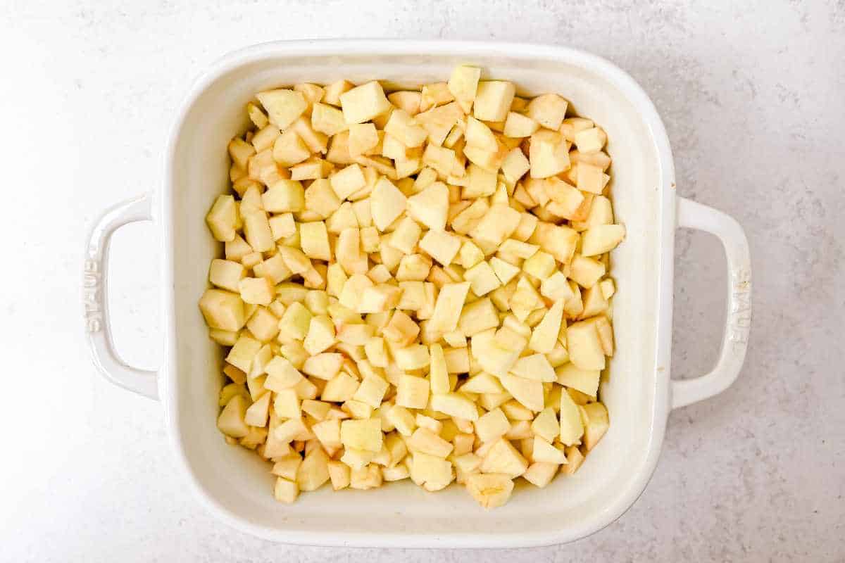 chopped fresh apples in a white dish on a white background.