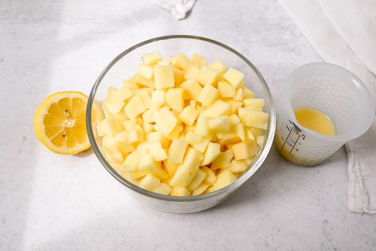 bowl of chopped apples with half a lemon and melted butter.