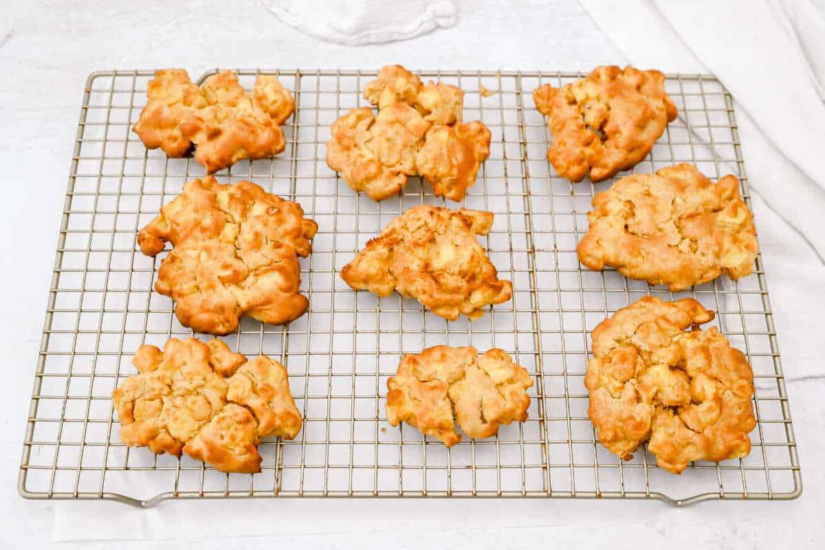 9 apple fritters on a baking rack.