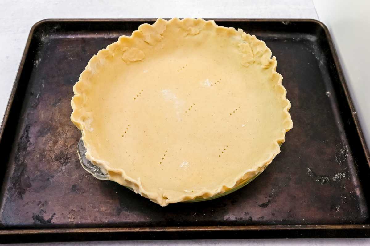 unbaked gluten-free pie crust in a pie plate on a sheet pan.