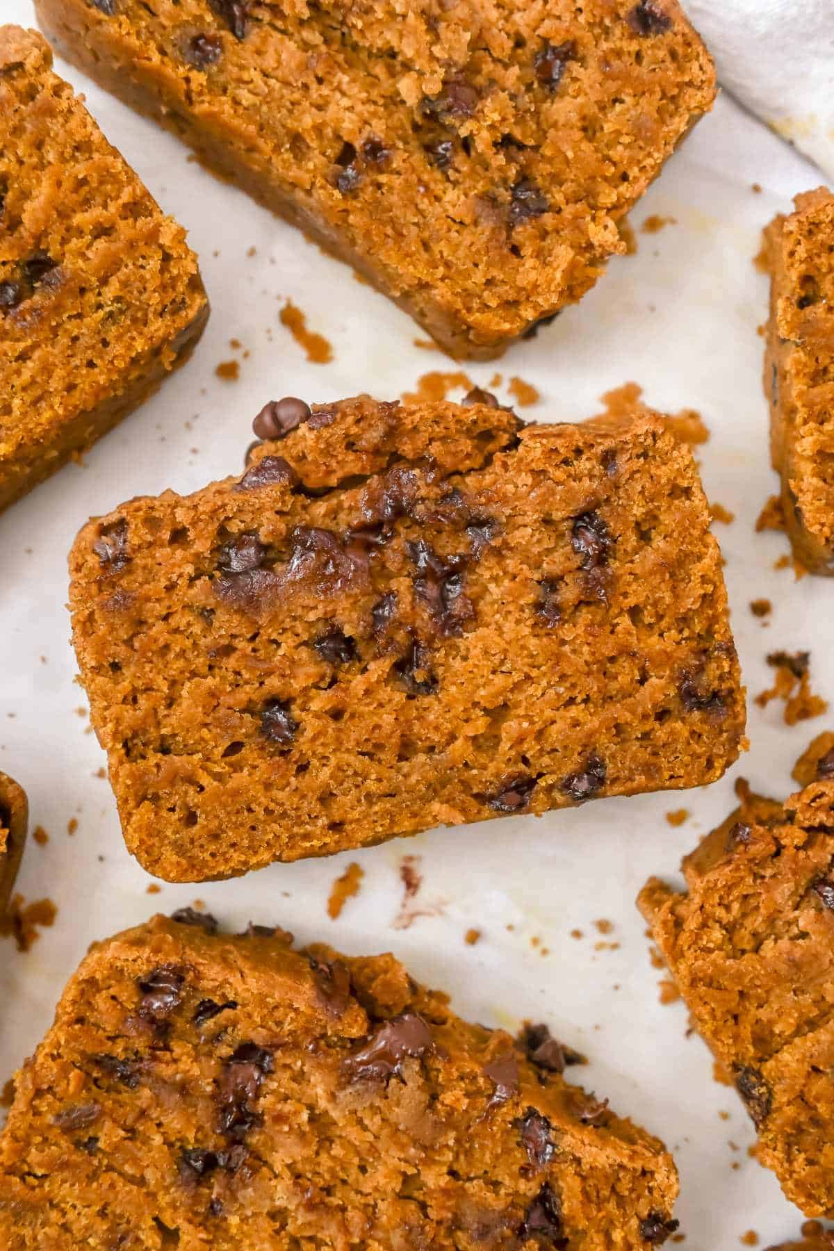 one slice of pumpkin bread in the middle on a white background with other slices around.