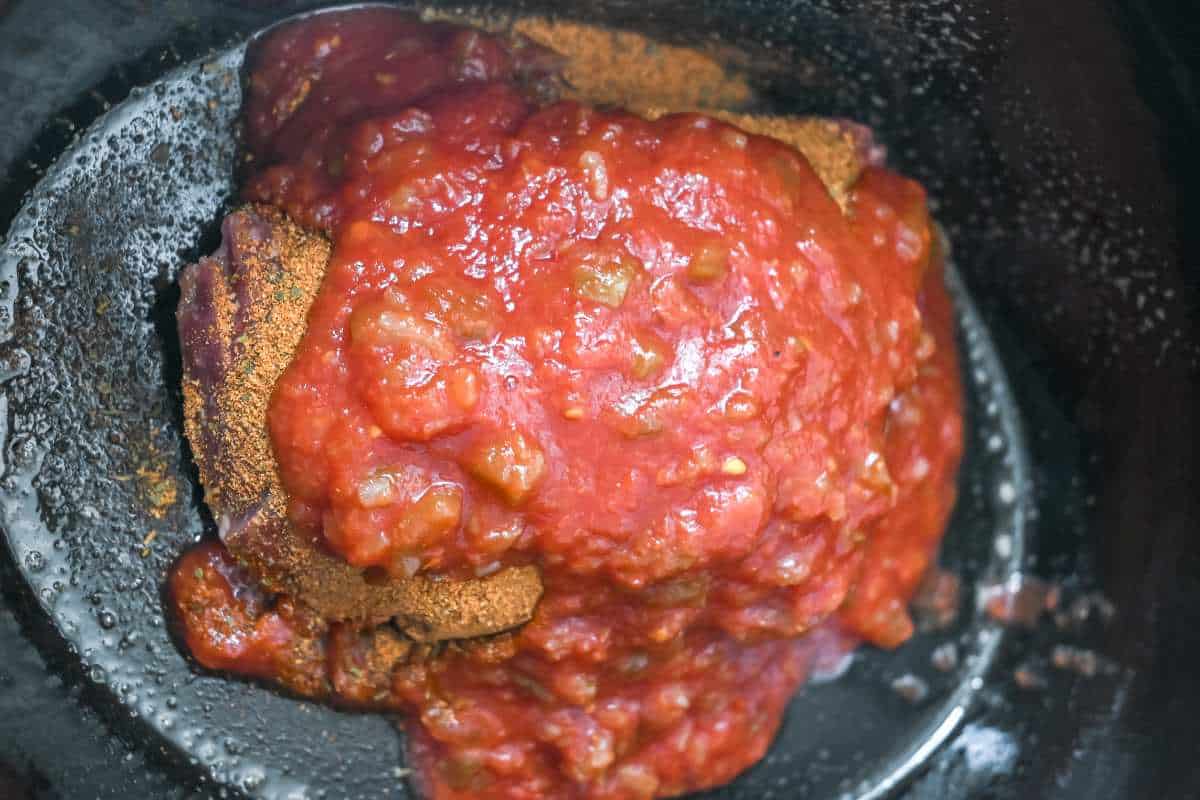 uncooked taco meat ingredients in a crock pot.