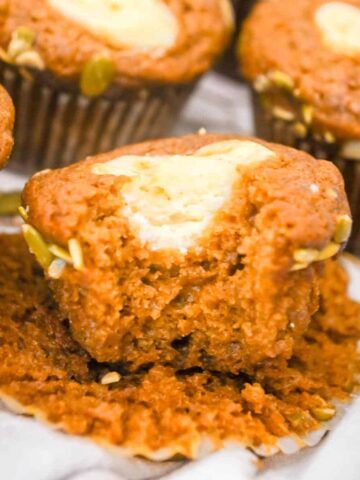 featured image of starbucks pumpkin muffins with a bite take out and topped with cream cheese filling.