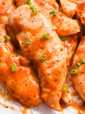 homemade frank's buffalo wing sauce on chicken tenders topped with green onions.