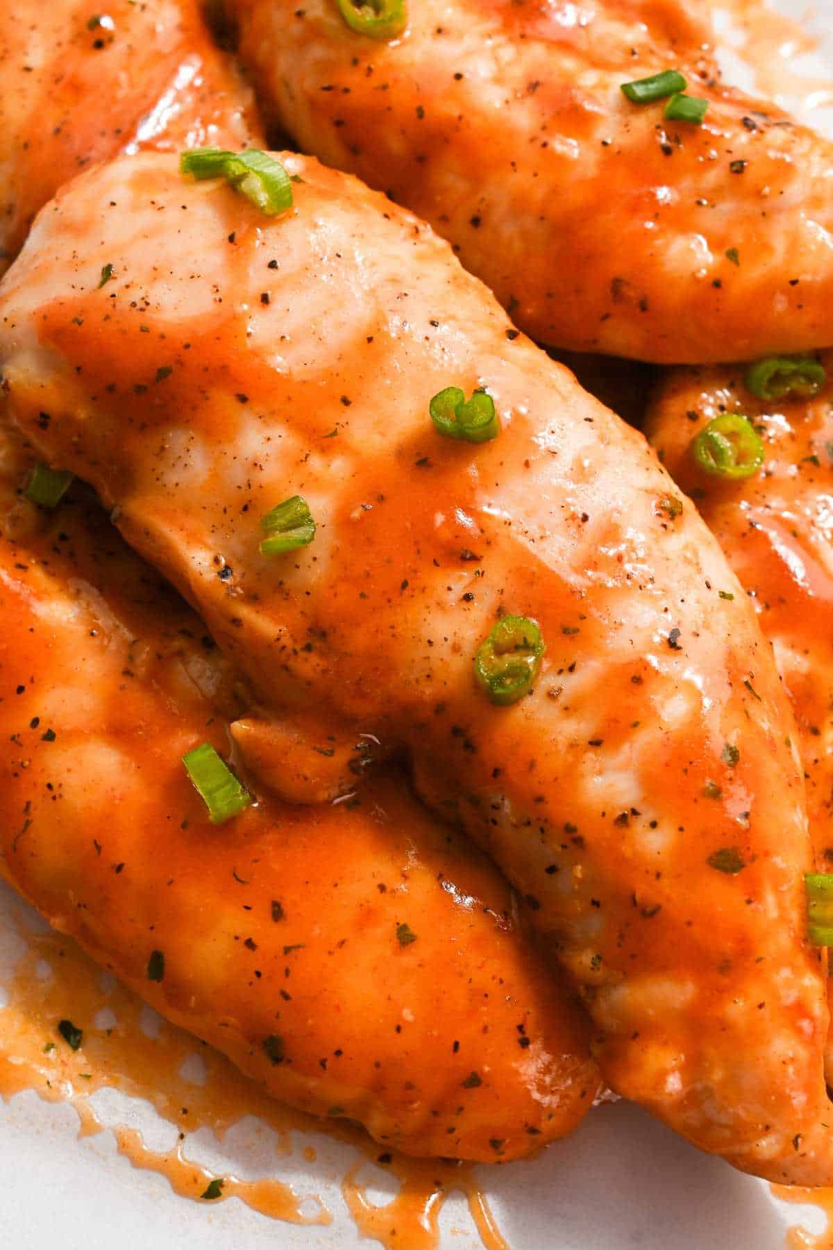 full shot of buffalo chicken tenders with no breading topped with green onions.