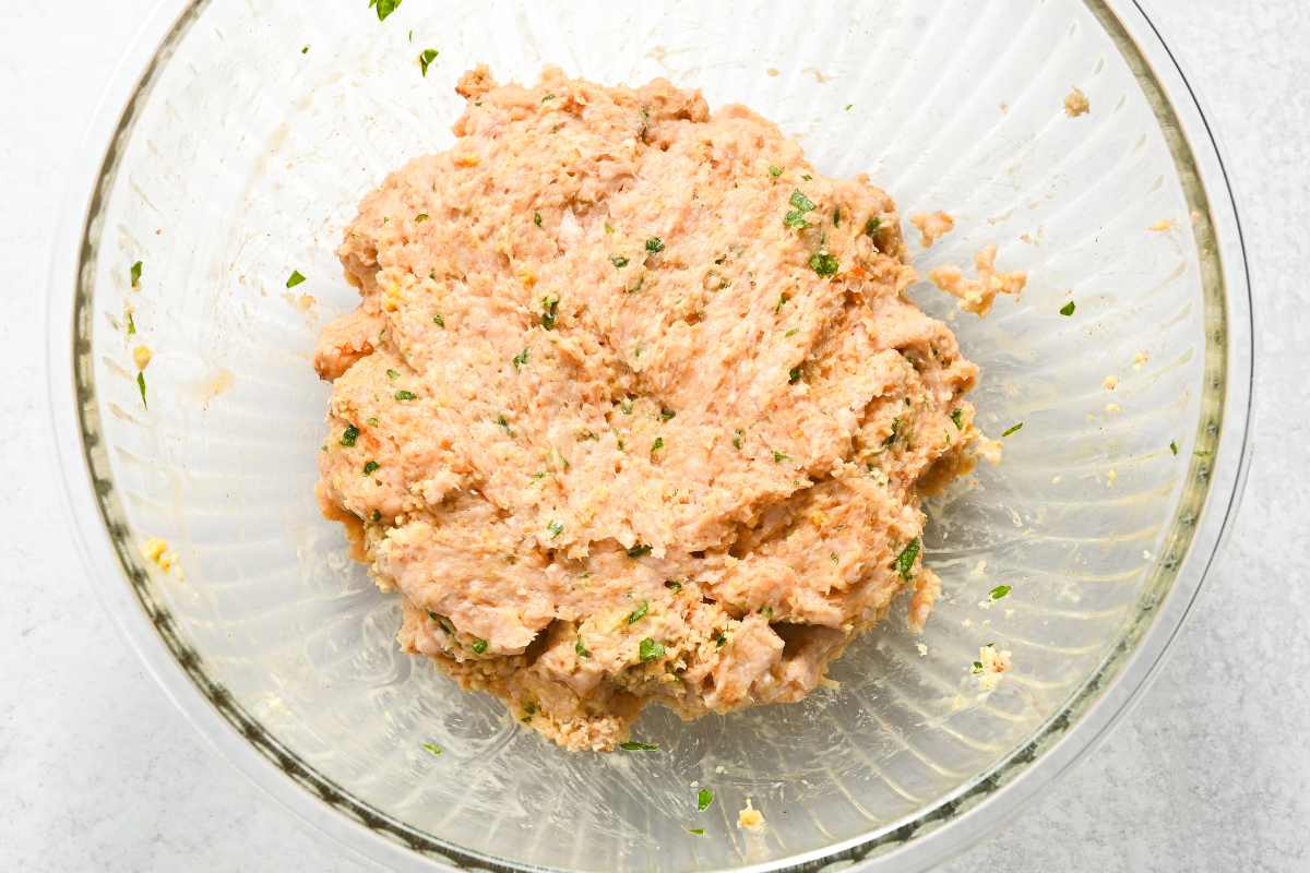 raw chicken burger mixture in a glass bowl.