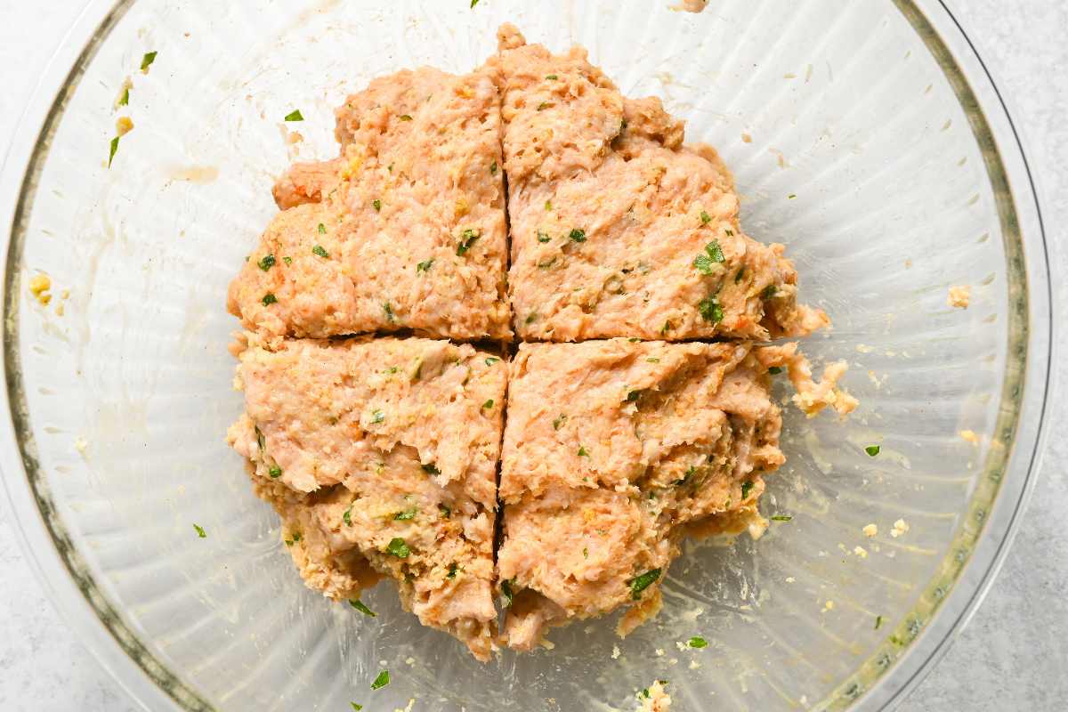 scored meat mixture in a glass bowl.