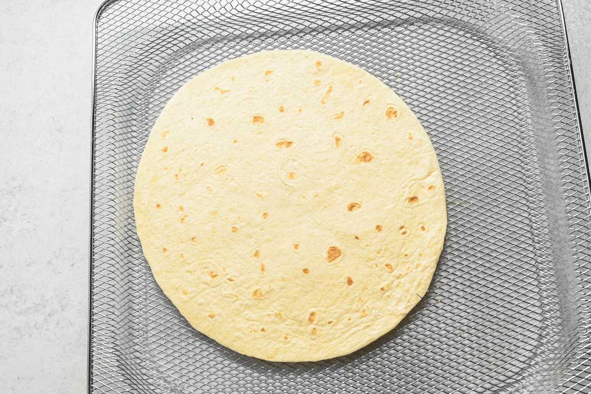 plain tortilla on an air fryer tray.